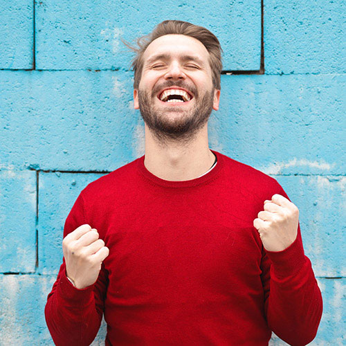 Laughing man in a red shirt against a blue wall